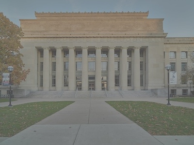 Large building with greek style columns and design at the top.
