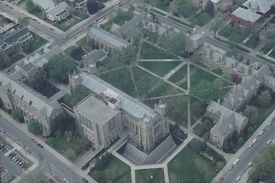 Outdoor aerial view of large stone buildings and green areas with trees.
