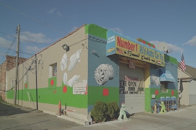 A shop called Number 1 Al’s Auto Care Fix (english and arabic) is painted outside with pictures of different car parts