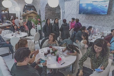 A family gathers around tables at a Filipino restaurant to celebrate a baptism.