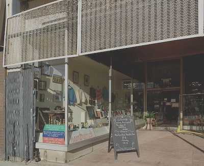 Store front with chalkboard in front of the store reading “A Collectible Clothing Boutique. A Place for Something Unique.”
