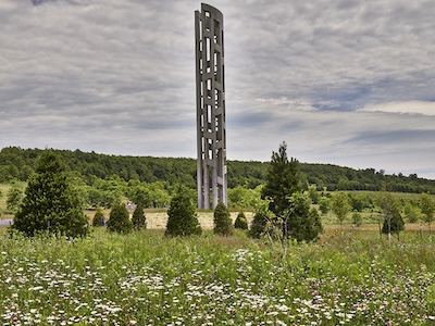 Grey obelisk in a field with trees 