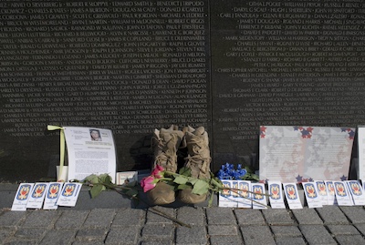 Close up photo of the Vietnam War Memorial in Washington, DC on Veterans day. There are soldier&rsquo;s boots, letters, photos, flowers, and other sentimental items placed in front of the memorial