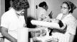 Photo, "Baby being weighed by nurse," IHS, 1887-1969, Photo Courtesy of the Indian Health Service/U.S. Department of Health and Human Services Photo, "Baby being weighed by nurse," IHS, 1887-1969, Dept. of Health