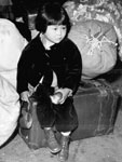 Photo, A young evacuee of Japanese ancestry waits with the family baggage before leaving by bus for an assembly center in the spring of 1942, 04/1942, Department of the Interior. War Relocation Authority, NARA Photo, A young evacuee of Japanese ancestry, 04/1942, Department of the Interior